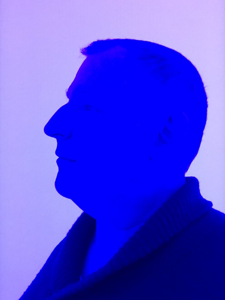 a blue profile of a face of NonAnoN - an NFT curator and artist - looking at his work