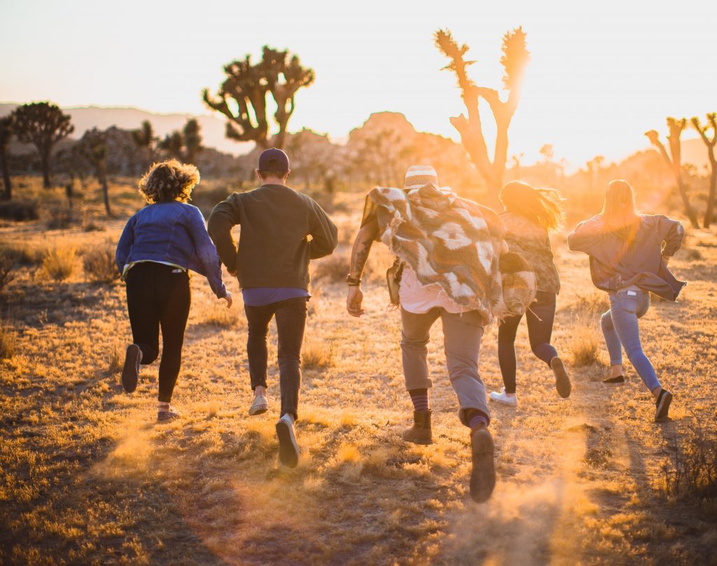 a group of nft artist running through the desert at sunset to reach out for the NonAnoN community